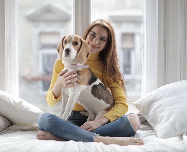 woman-in-yellow-cardigan-sitting-on-white-bed-with-dog-3971439.jpg